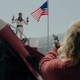 Betty's mom aims a gun at a cult leader wearing an Evel Knievel outfit next to a cartoonish rocketship.